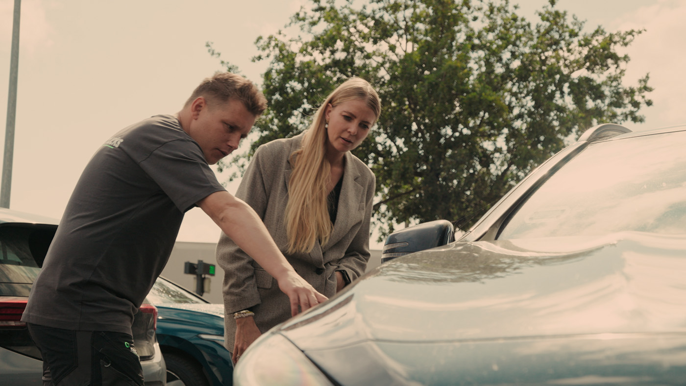 Kund granskar bilskada med Carbucks-tekniker före reparation