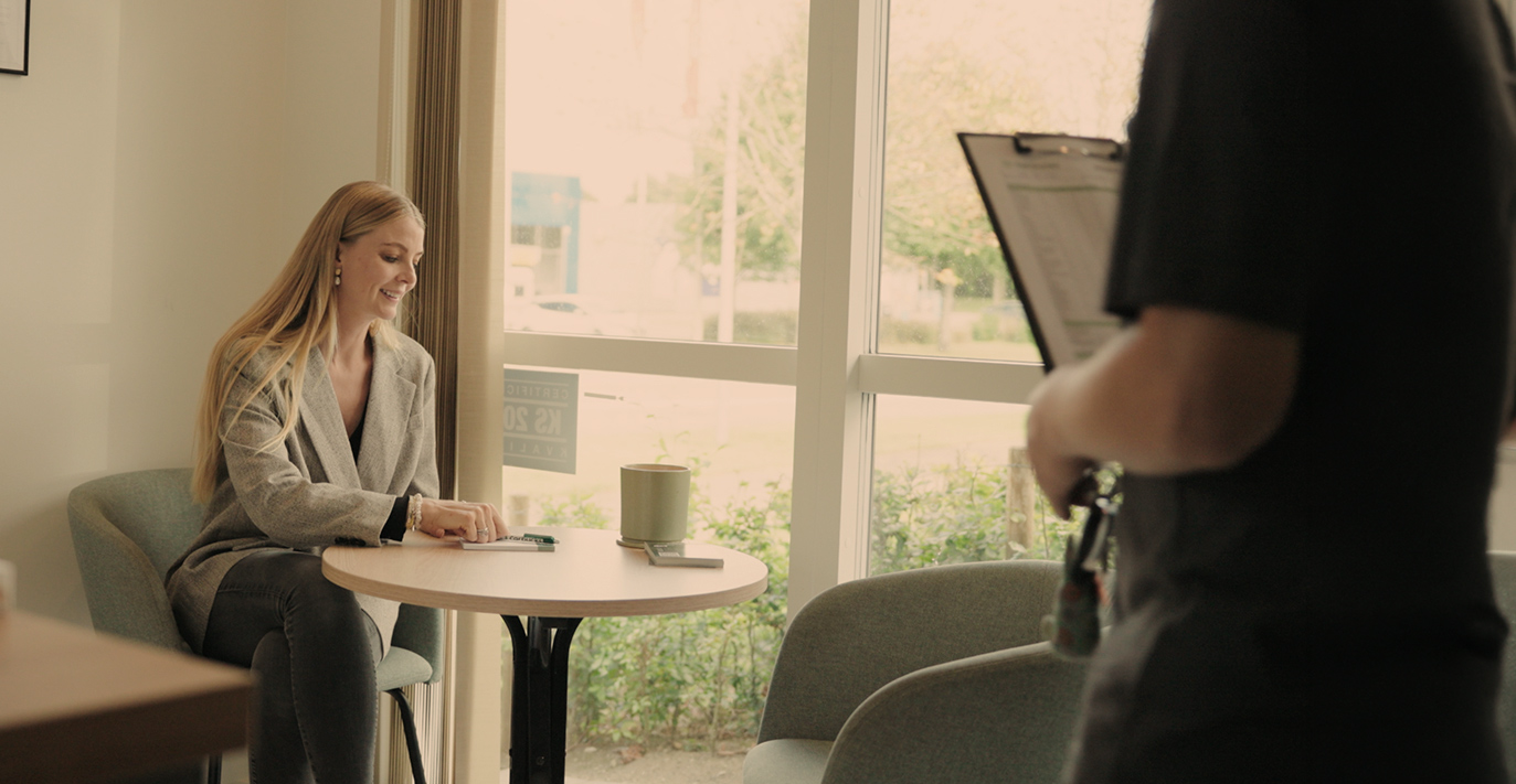 Kunde venter i roligt loungeområde med kaffe under bilreparation