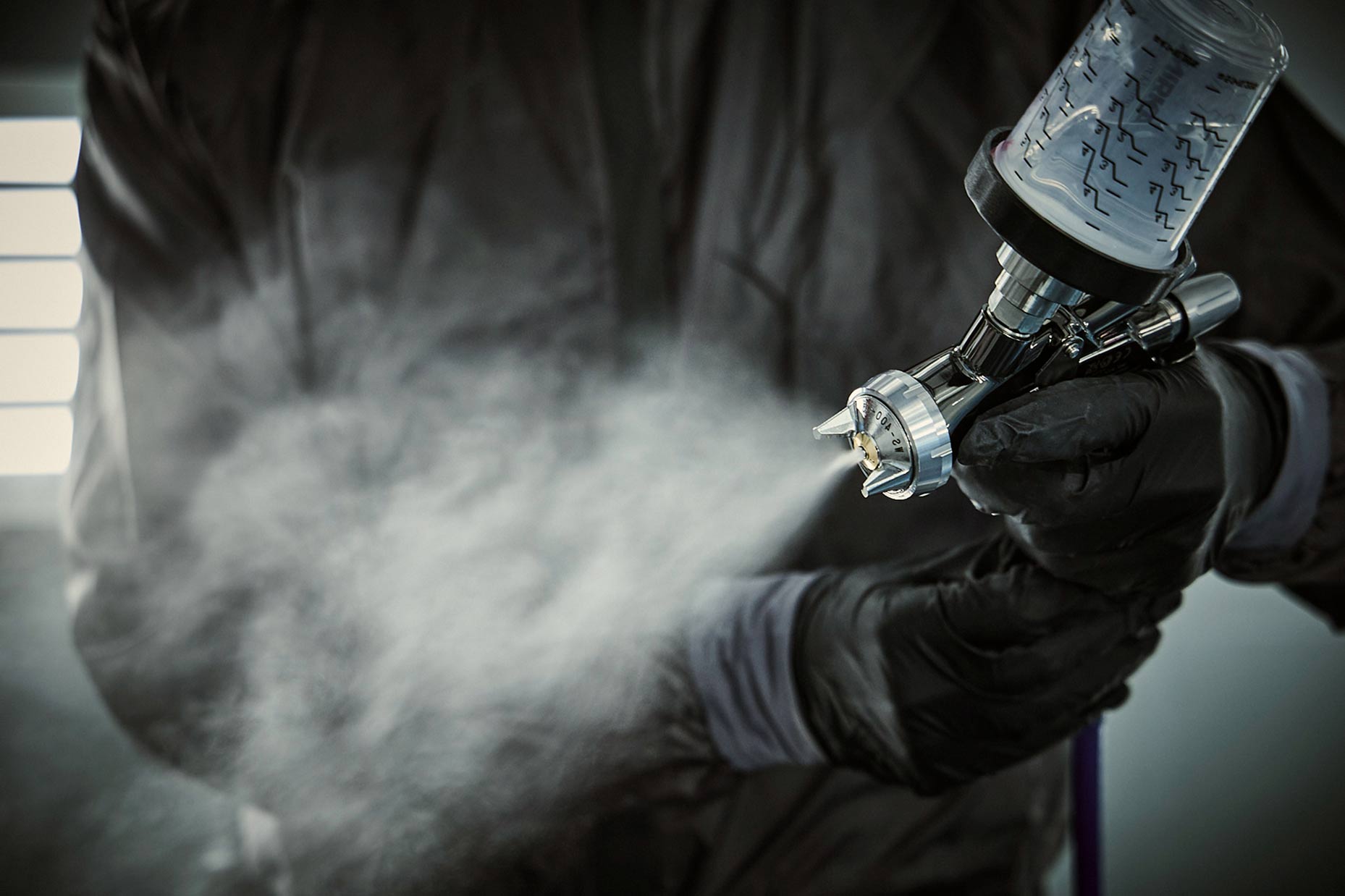 Lakering af bil med sprøjtepistol under reparation hos Carbucks