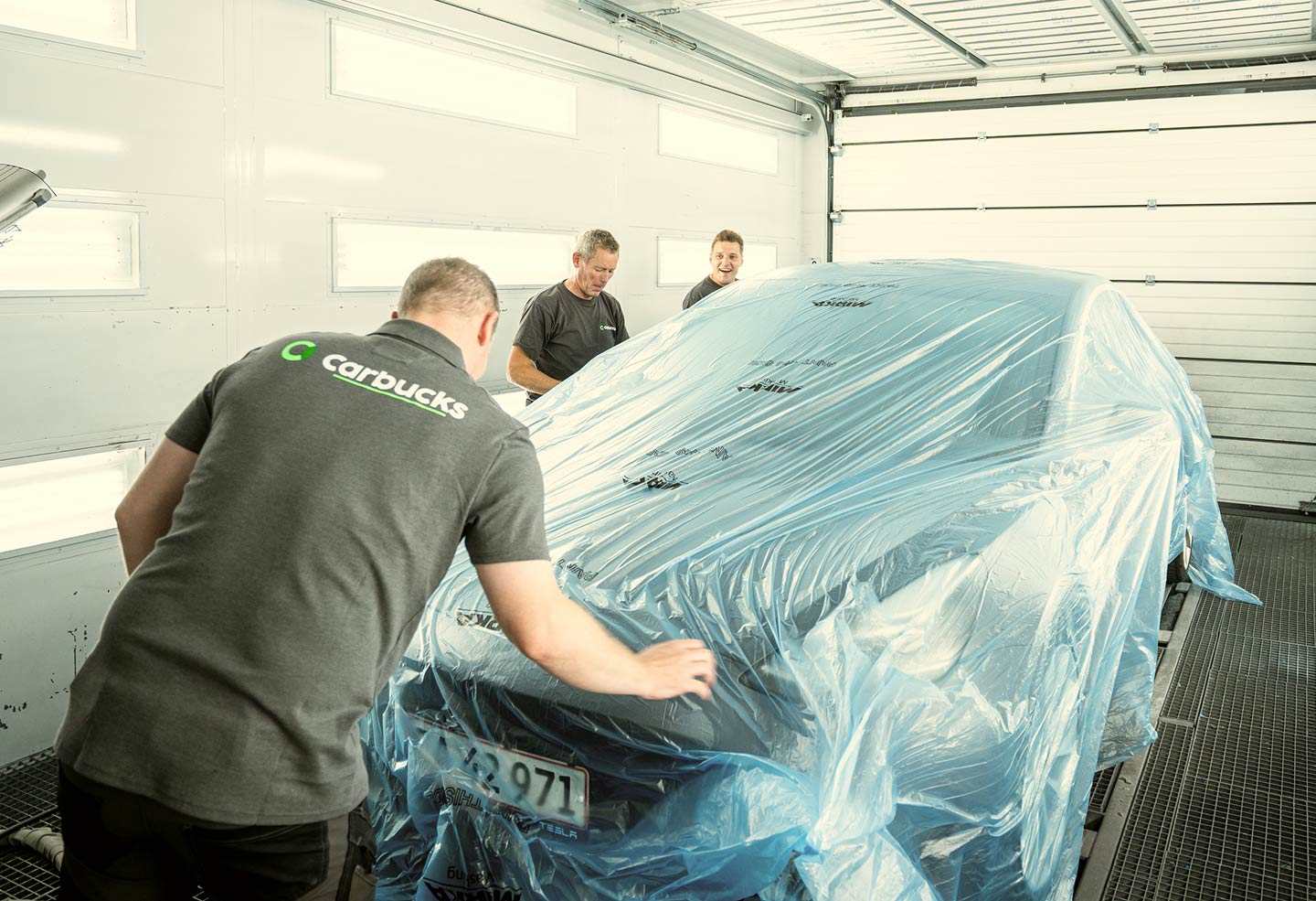 Bil afdækkes til reparation af flere teknikere i værkstedsboks hos Carbucks
